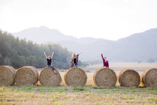 A group of friends waving from a row of straw bale