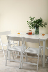 White kitchen table with tea and plant in bright room