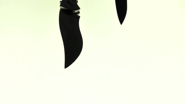 Two sharp steel knives, one ordinary second throw-out, fly by in front of the video camera.