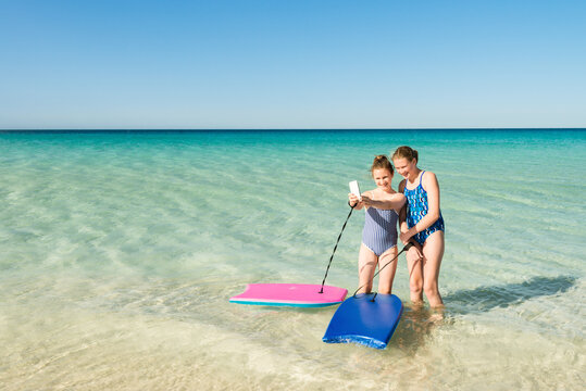 two teenage girls taking a selfie at the beach