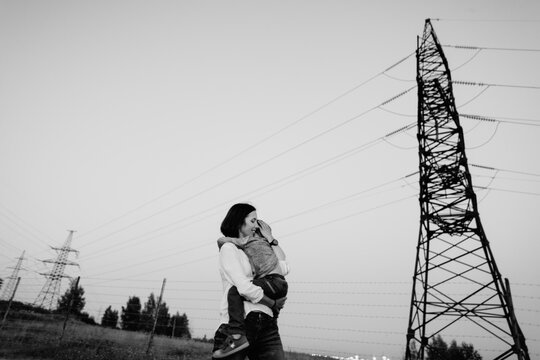 Mother carrying her son in the field ander towers of power