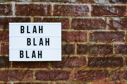 The words Blah Blah Blah on a lightbox on a brick wall