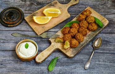Fresh vegan dish-  falafel balls from spiced chickpeas  with lemon   and garlic yogurt sauce  on wooden rustic table.