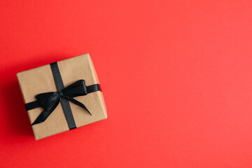 Gift box with black bow on red background