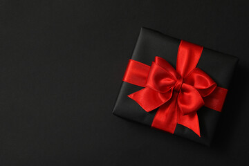 Gift box with red bow on black background