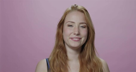 Blonde woman blowing kiss, pink background, slow motion