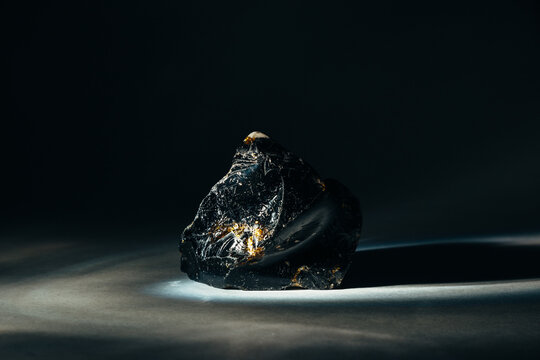 Black Obsidian Stone With Edges Illuminated By Faint Light