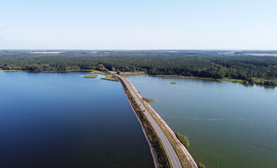Top view of the road bridge dam over a huge forest lake