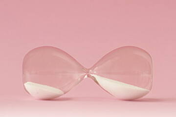 Hourglass lying on pink background - Concept of time and woman - 380562845