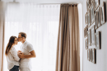 Lovely young parents with newborn baby at home, caring mom hold little daughter in arms, loving husband gently kiss beautiful wife, enjoy tender moments, happy family concept