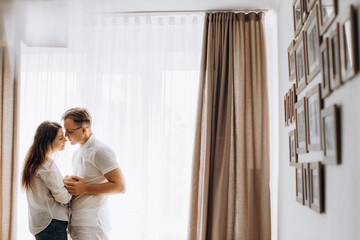Lovely young parents with newborn baby at home, loving mother and caring father gently hold little daughter in arms, enjoy tender moments, happy family concept