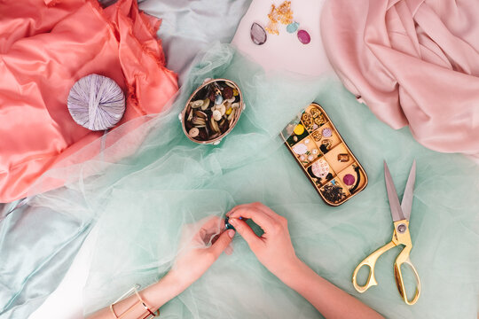 Woman Sewing Pearls on a Pastel Fabric