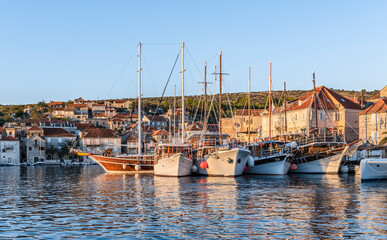 Fototapeta premium View of the promenade of Milna, Croatia, with yachts, ships and houses at sunset