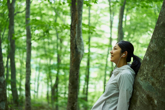 木にもたれて音楽を聴く女性