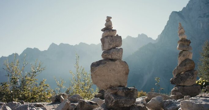 Stone or rock stack or pile or cairn zen meditation hiking sign in autumn protected mountain nature in Alps silhouette close up lens flare beautiful fall light