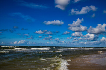 sunny day on the shores of the Polish Baltic Sea with blue sky and water waves