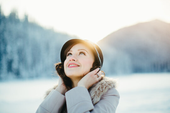 Young stylish beautiful girl smiling on snow covered winter lake
