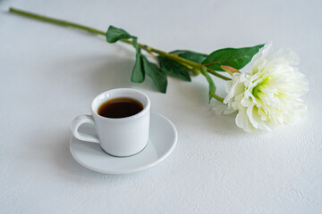 there is a mug of coffee on the table next to a flower