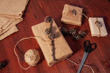 Handmade paper boxes with scissors on wood with pine cone. Flat lay. Top view