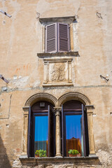 Fototapeta na wymiar Old house facade, big windows, open shutters. in popular touristic village Garda