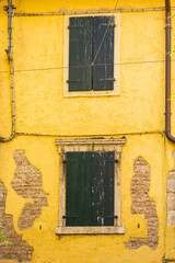 Old yellow house facade, closed green window shutters
