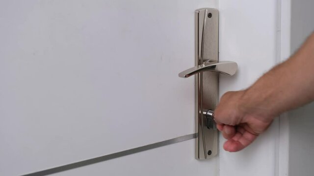 The man opens the door of the room with the key.