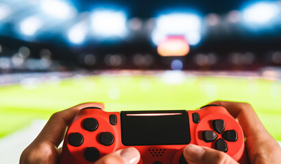 Young man having fun playing online soccer video games - Close up red magma game pad on tv background - Gaming entertainment and youth millennial generation lifestyle concept