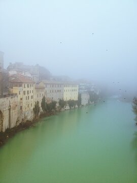 Group of typical houses overlooking a river surrounded by fog