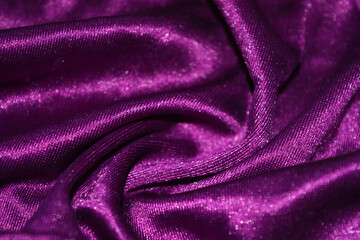 Bright colorful, rich velvet purple background with overflow and ebb. An unusual shaggy purple fabric with curves and waves is located on a flat surface, an unusual look.