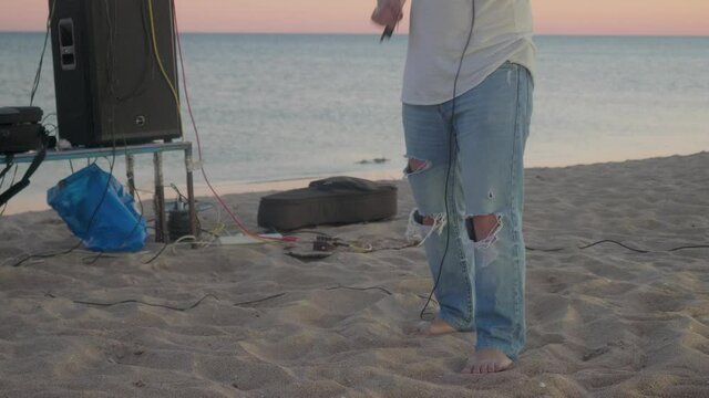 Musician's legs in torned jeans. Man plays the violin during summer sunset.