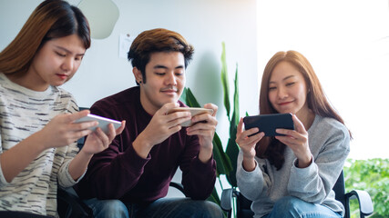 Group of young people using and playing games on mobile phone while sitting together