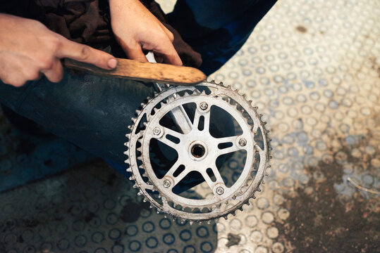 Man brushing a chain wheel.