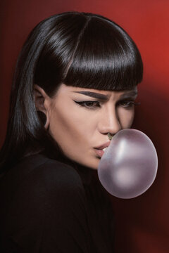 Beautiful woman in studio blowing a gum balloon