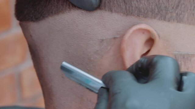 Barbero afeitando con navaja en barber shop