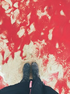 Feet in boots standing in a pool of blood on a beach.