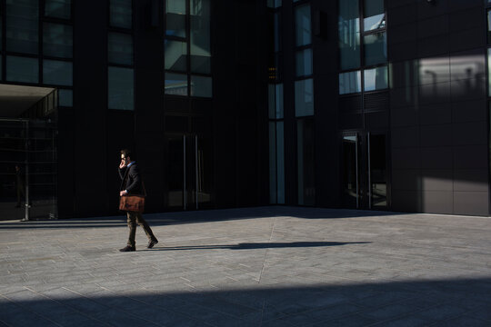 Businessman on the cell walking outside of the building office