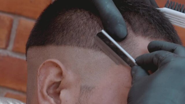 Afeitando cráneo con navaja a modelo masculino en barbería 