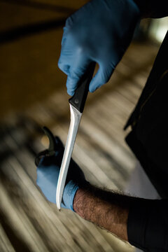 Sharp fillet knife in hands of man wearing rubber gloves
