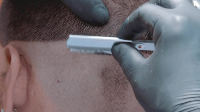 Peluquero afeitando con navaja a modelo masculino en barber shop