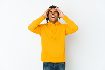 Young african american rasta man laughs joyfully keeping hands on head. Happiness concept.