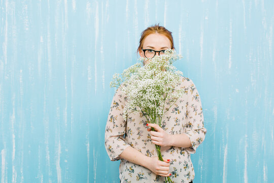 Ginger woman holding a bouquet of Paniculata flowers.