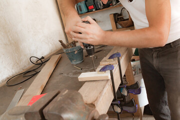 Male carpenter working on old wood in a retro vintage workshop.