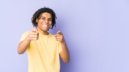 Young african american rasta man cheerful smiles pointing to front.