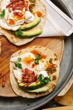 Overhead view of two tasty looking breakfast tacos on a wooden platter.