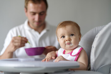 Father feeding baby daughter in high chair