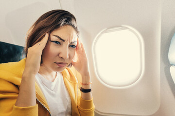 Suffocating asian woman is flying on an airplane and suddenly felt a strong attack of migraine and headache. The health condition did not allow the passenger to easily transfer the flight