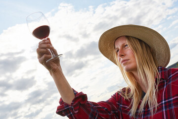 Woman looks critically at a glass of red wine