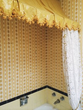 Outdated yellow bathroom with wallpaper