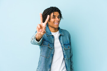 Young black man wearing a jeans jacket showing number two with fingers.