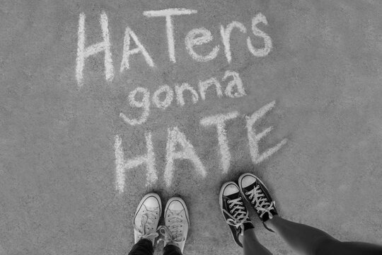 Two kids standing above chalk words that say Haters gonna Hate
